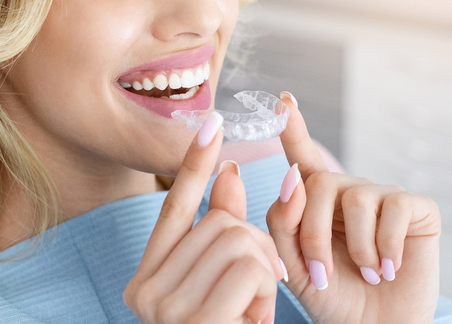 Patient smiling at dentist holding clear aligner